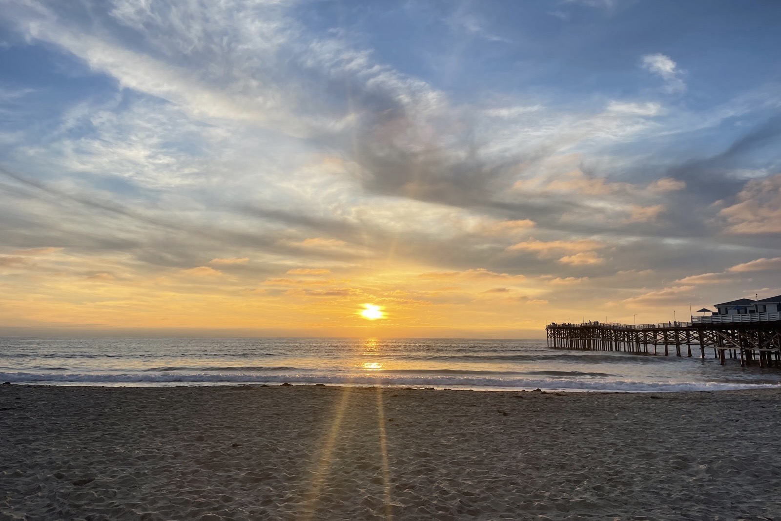 Crystal Pier at sunset seen from the beach, the full length of the pier extending over the water.